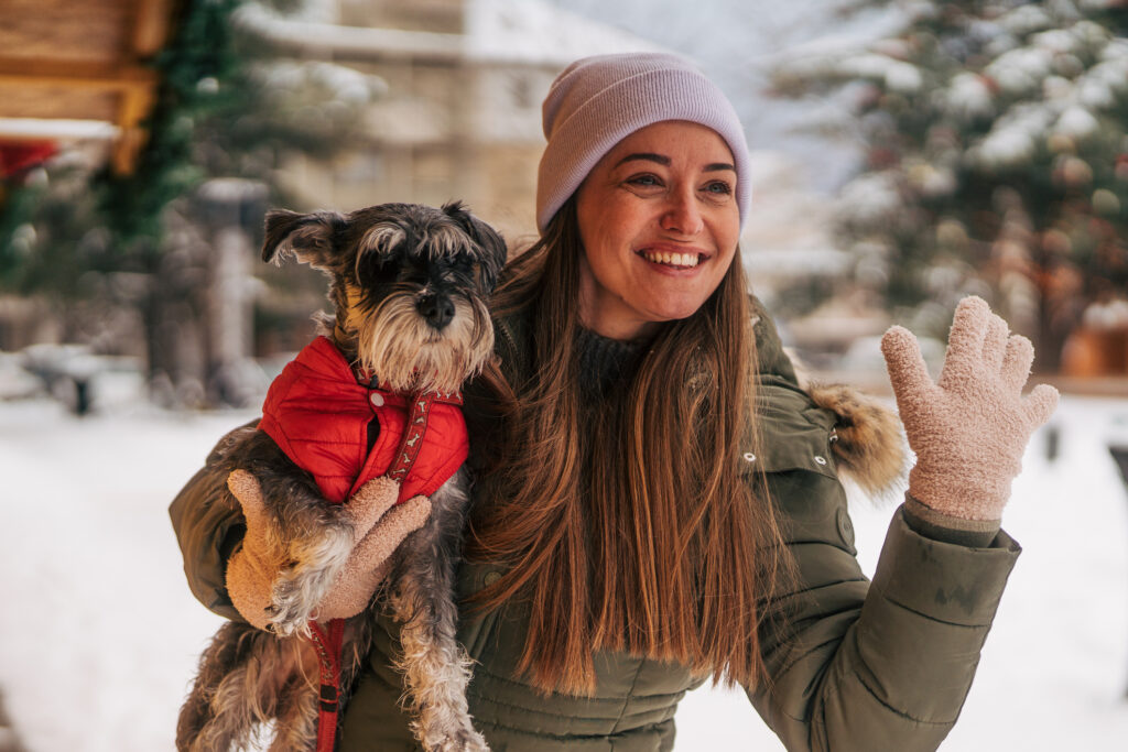 Woman holding miniature schnauzer enjoying winter snow